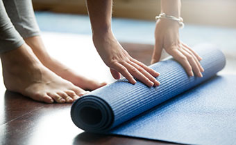 Woman's hands touching a rolled up Yoga Mat